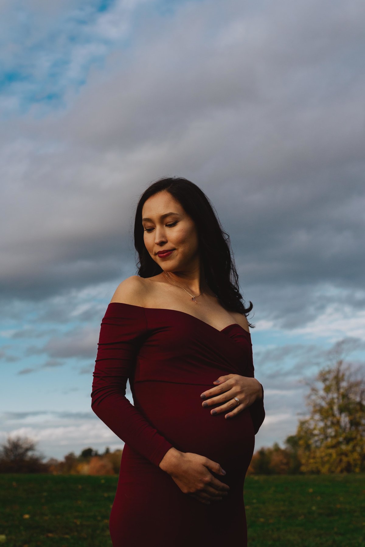 pregnant woman in a dress holding her belly at sunset