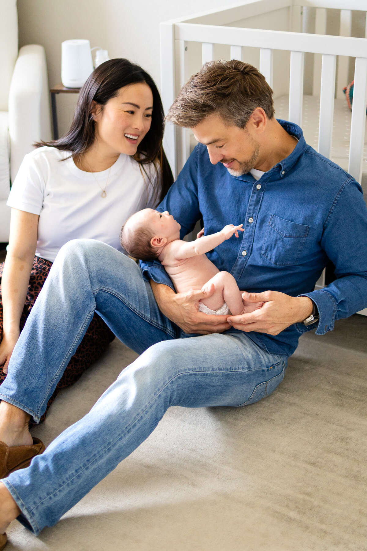 Father cradling baby while mother smiles beside, taken by San Francisco newborn photographer.