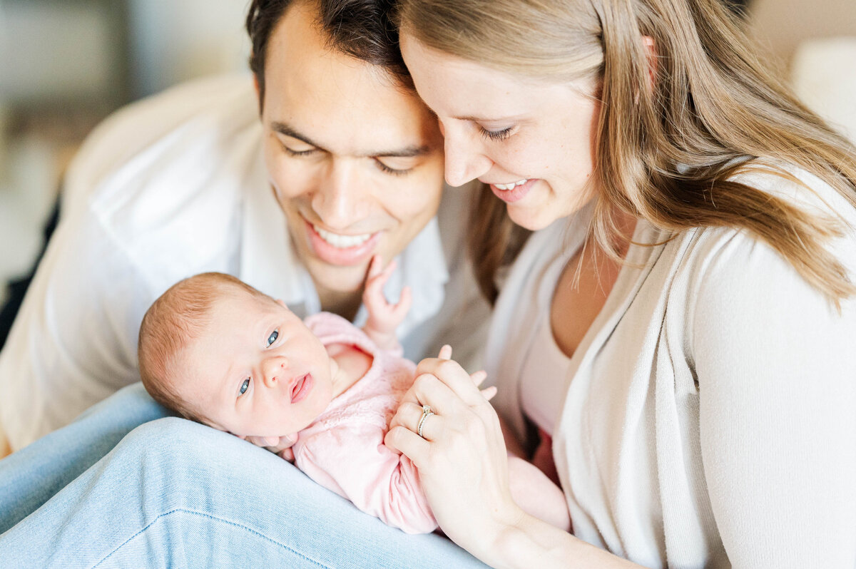 Mom and dad looking down at newborn girl taken in Westwood, MA by best Westwood newborn photographer