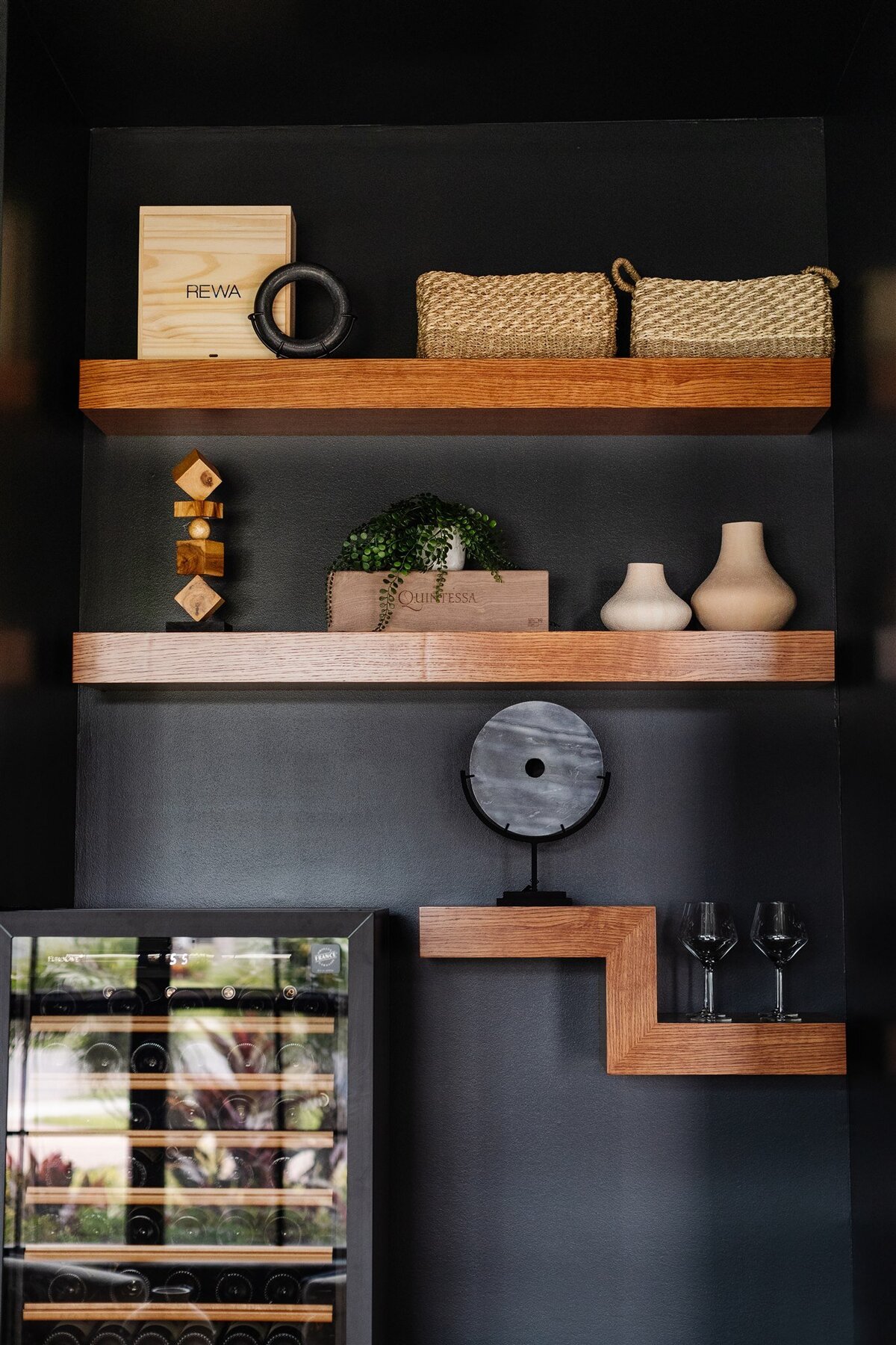 Wooden shelves with accents on black wall above wine cellar