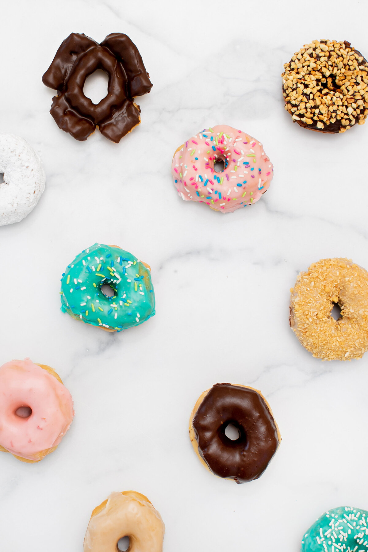 Assorted and Colorful Donuts on Marble Countertop - Daylight Donuts