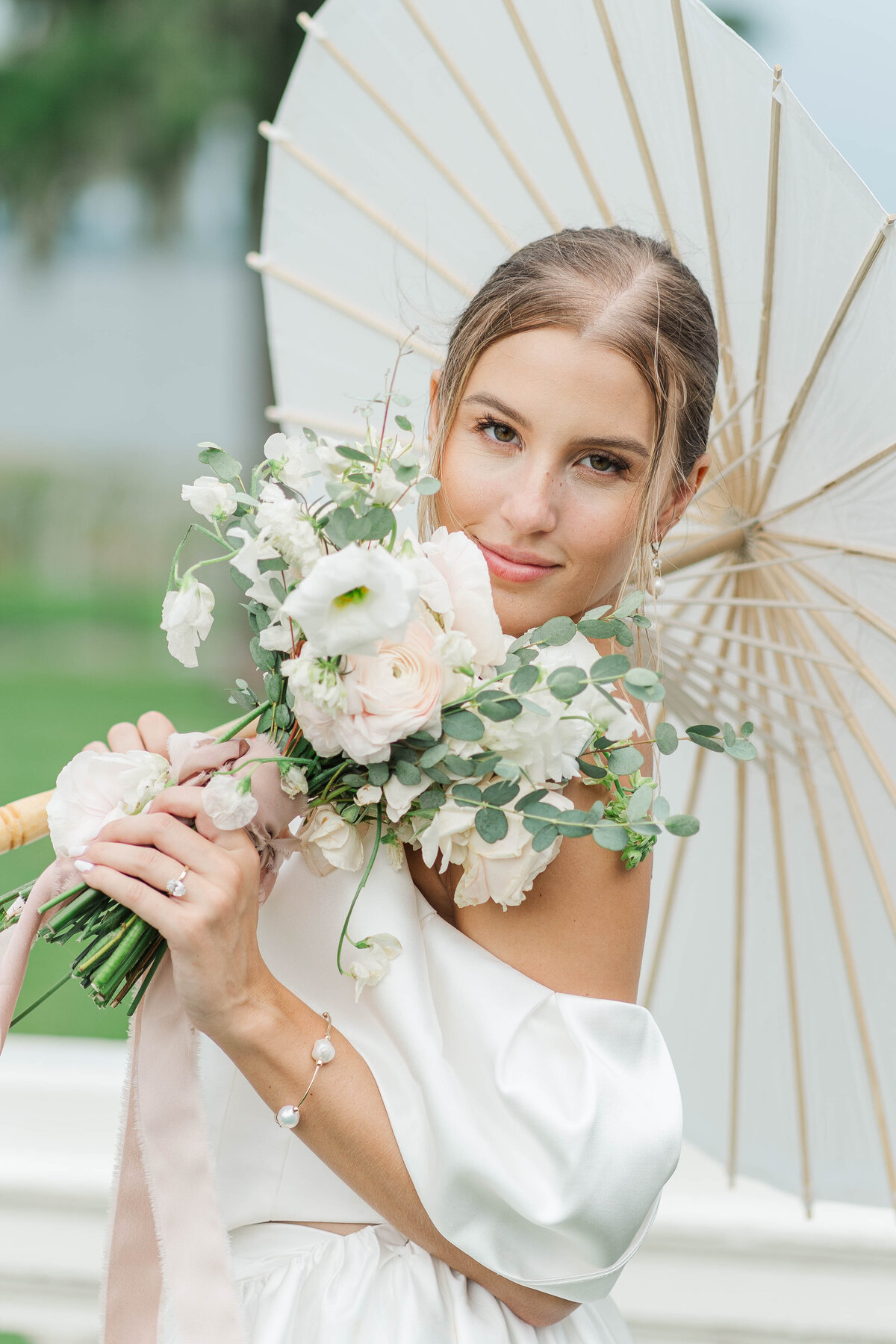 bride with a paper umbrella, close up, she is holding her bouquete