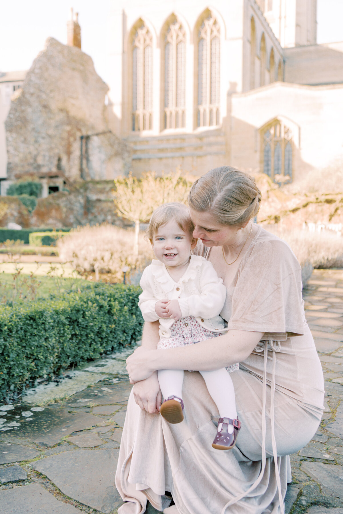 Mother kneels down with toddler daughter in the middle of an english garden by Savannah family photographer Courtney Cronin