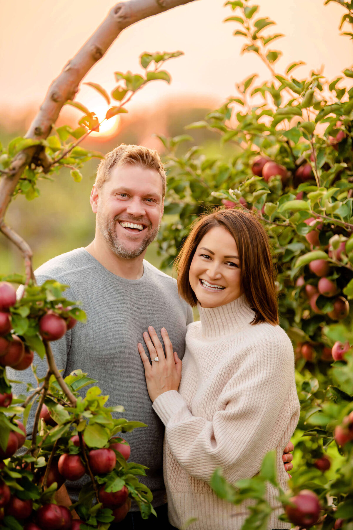 mom and dad hugging in an apple orchard for their fall family photos in Burlington, On