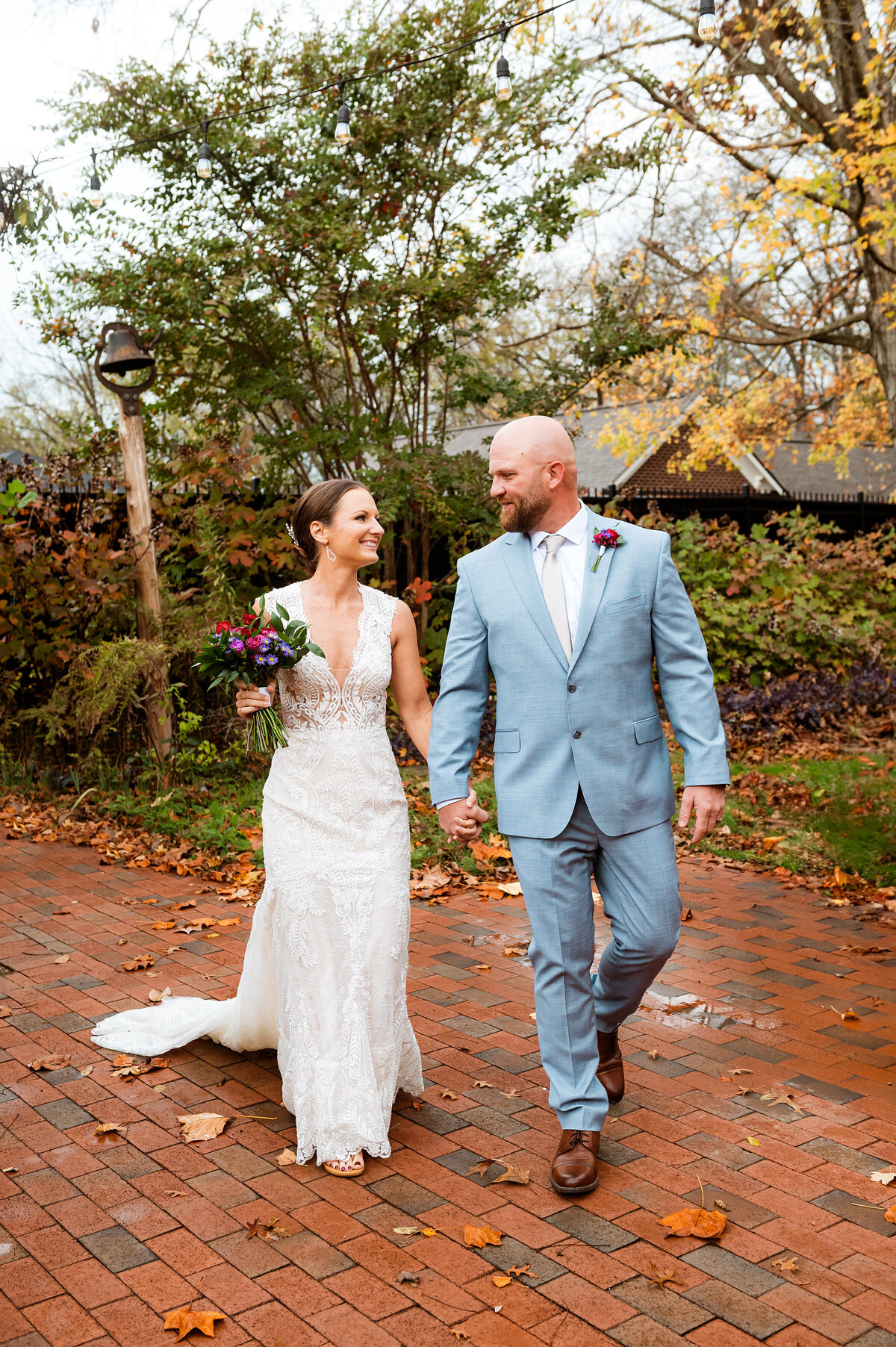 Newlyweds holding hands and walking in the fall foliage