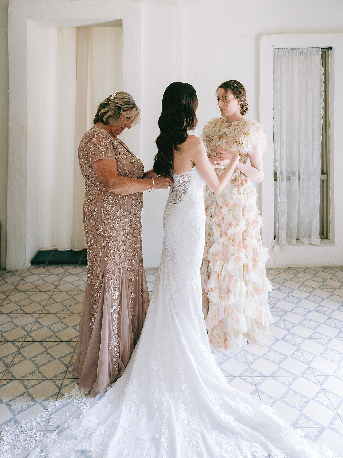 The bride gets dressed in the bridal suite at Villa Antonia assisted by her mother and maid of honor