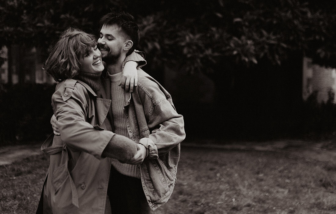 Nolan et Léa, vidéaste et photographe mariage vintage, enlacés et complices. Photographie en noir et blanc.