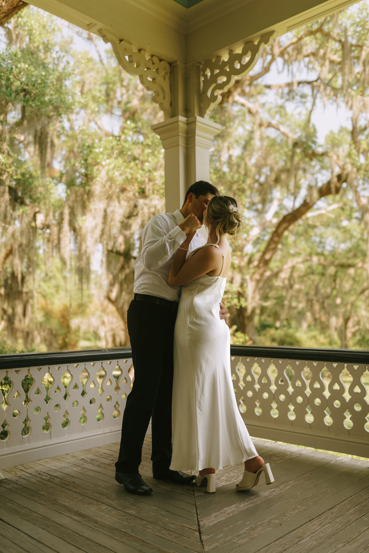 A wedding couple kissing on the porch of the Jefferson House at Rip Van Winkle Gardens. 