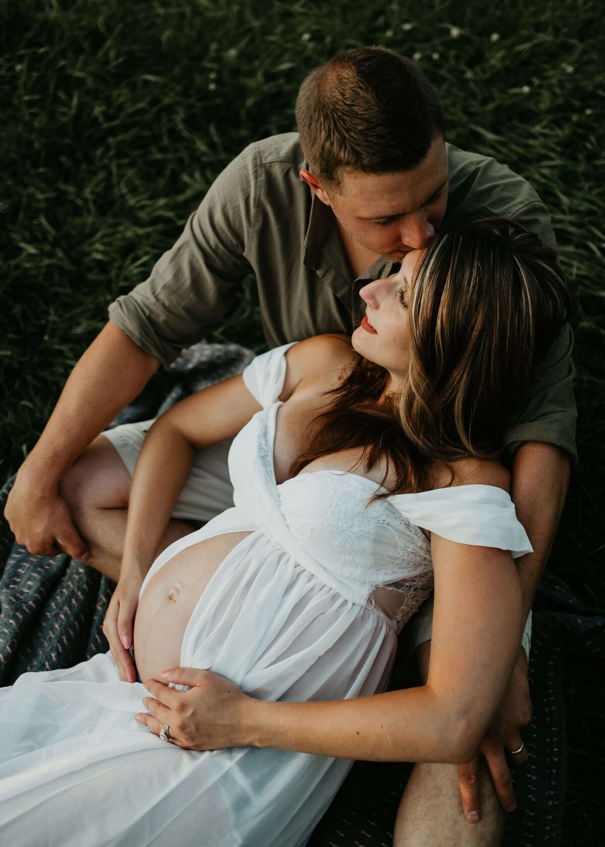 A pregnant couple enjoying a blanket in a field captured by a Pittsburgh maternity photographer.