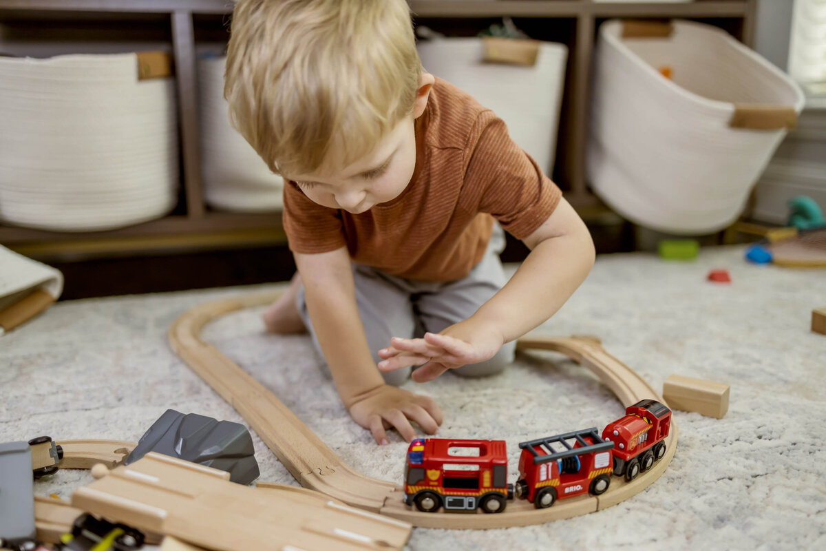 a boy plays with a wooden train in his home in frisco texas