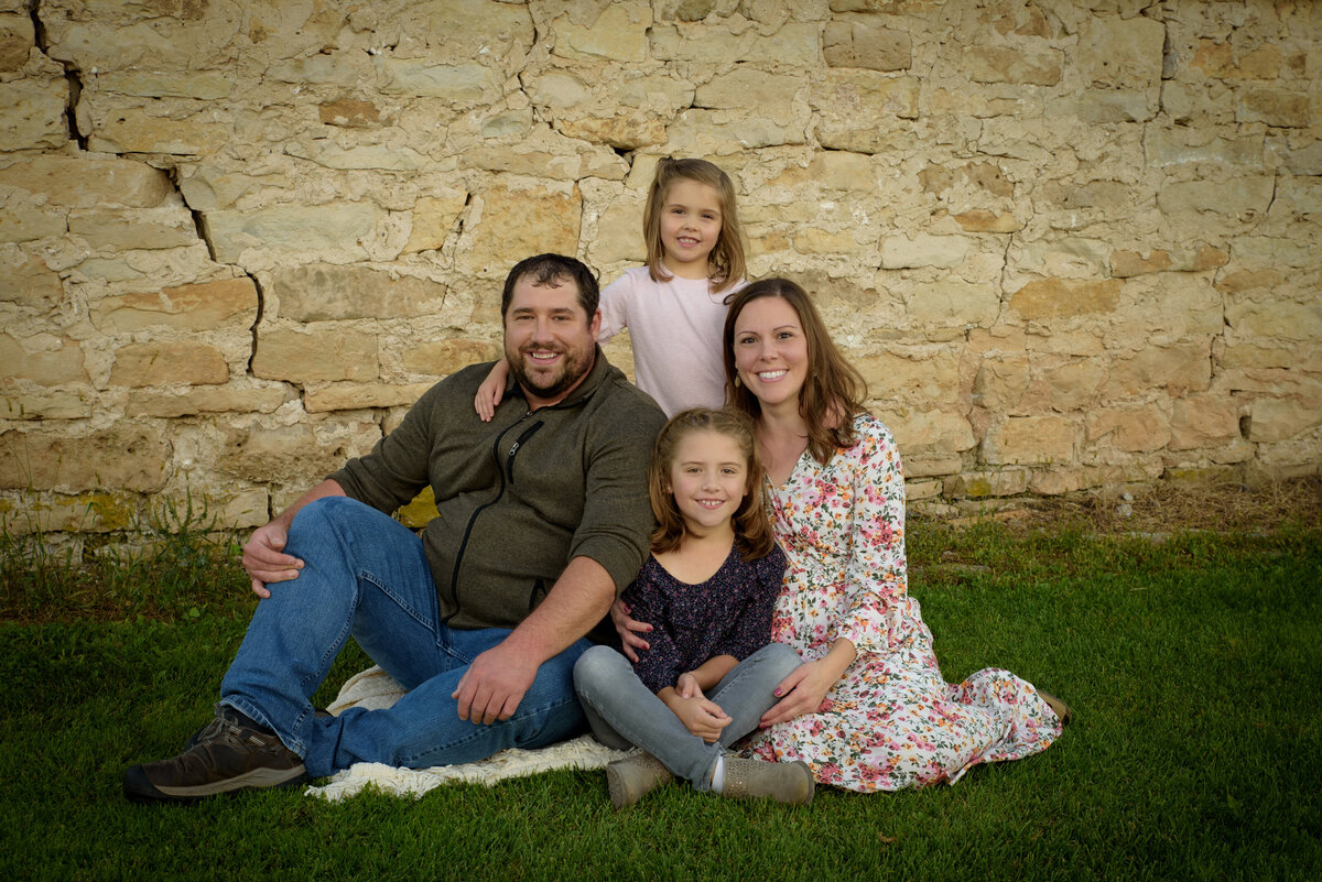 Young family snuggling on a blanket in front of a stone barn at Fonferek Glen County Park near Green Bay, Wisconsin.