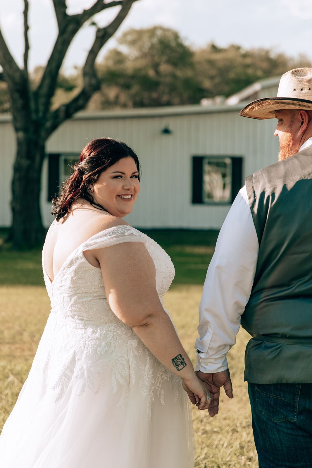 bride looks over her shoulder at the camera during couples portraits