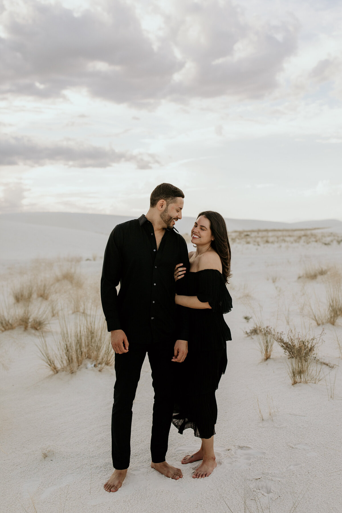 engaged couple standing together in the desert white sand dunes