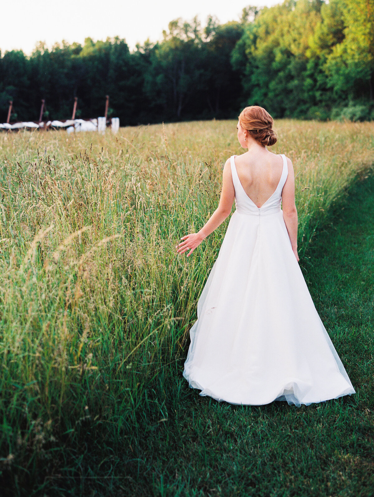 Bride walking through a grassy field