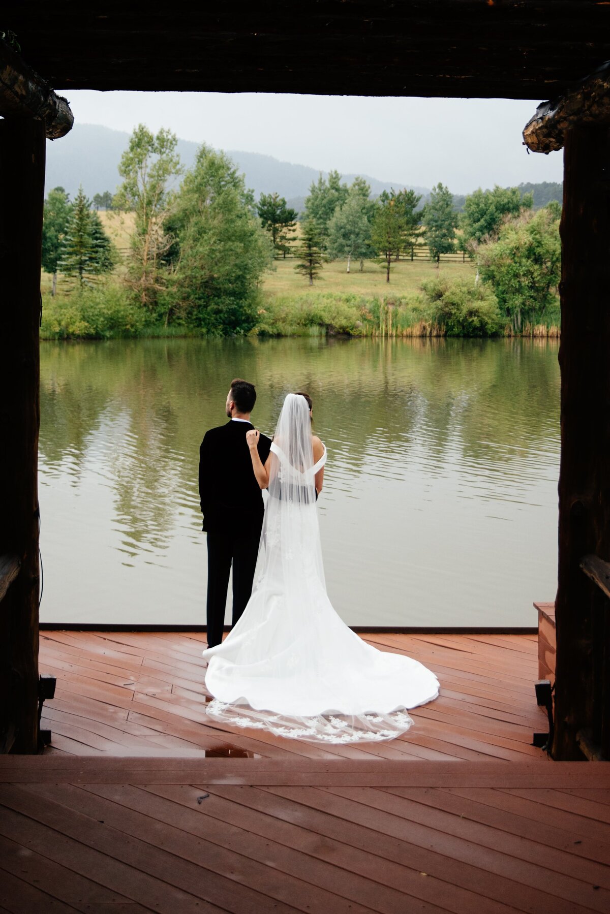 Bride and Groom look out at the pond at Spruce Mountain Ranch.