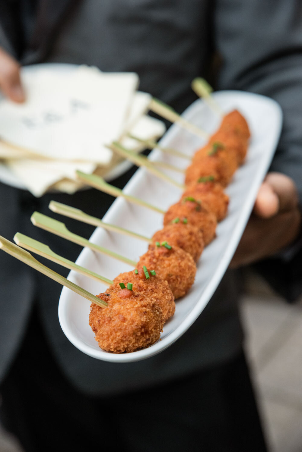 A person is holding a plate of food on sticks