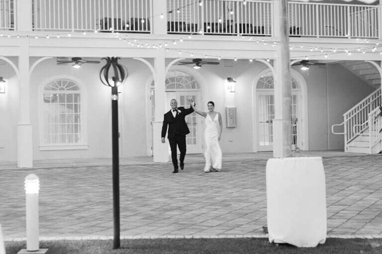  The bride and groom make their grand entrance, hand in hand, at a beautifully lit Florida Keys wedding venue, welcomed by their loved ones. Captured by Claudia Amalia Photography.