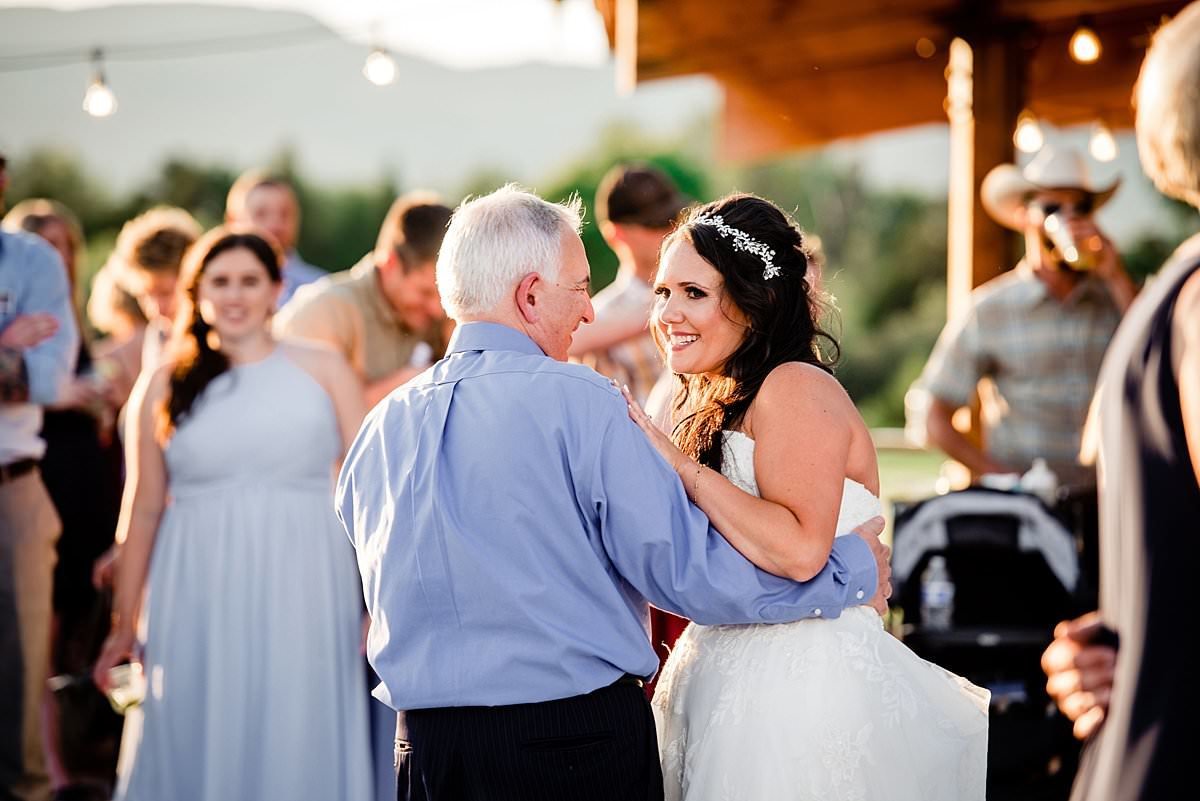 Bride smiling at her dad as they share a daddy daughter dance together
