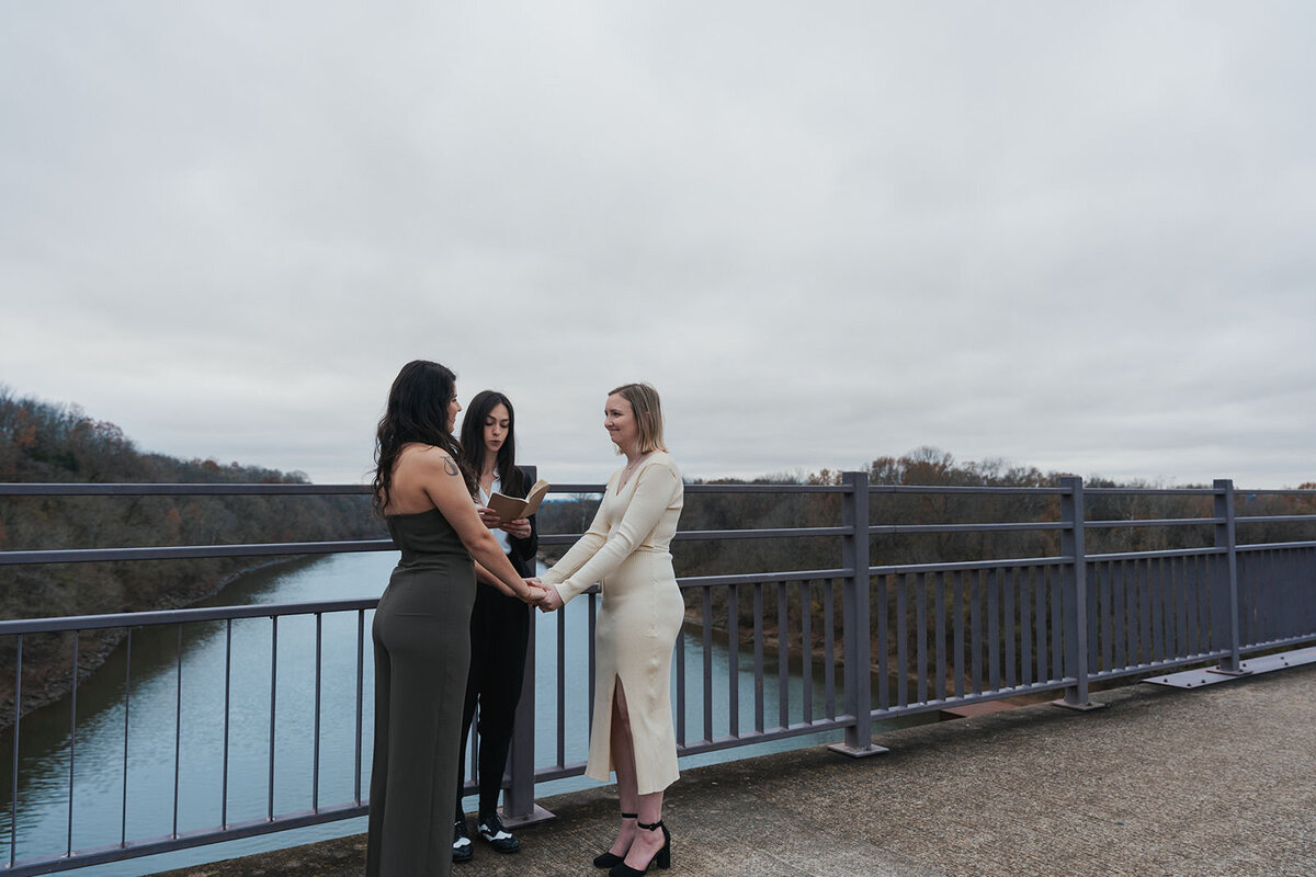 Women hold hands on the bridge of their Nashville Tennessee elopement 
