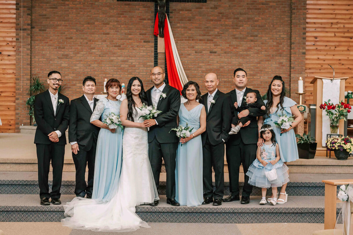 Bride and groom stand with their family at the front of the church.
