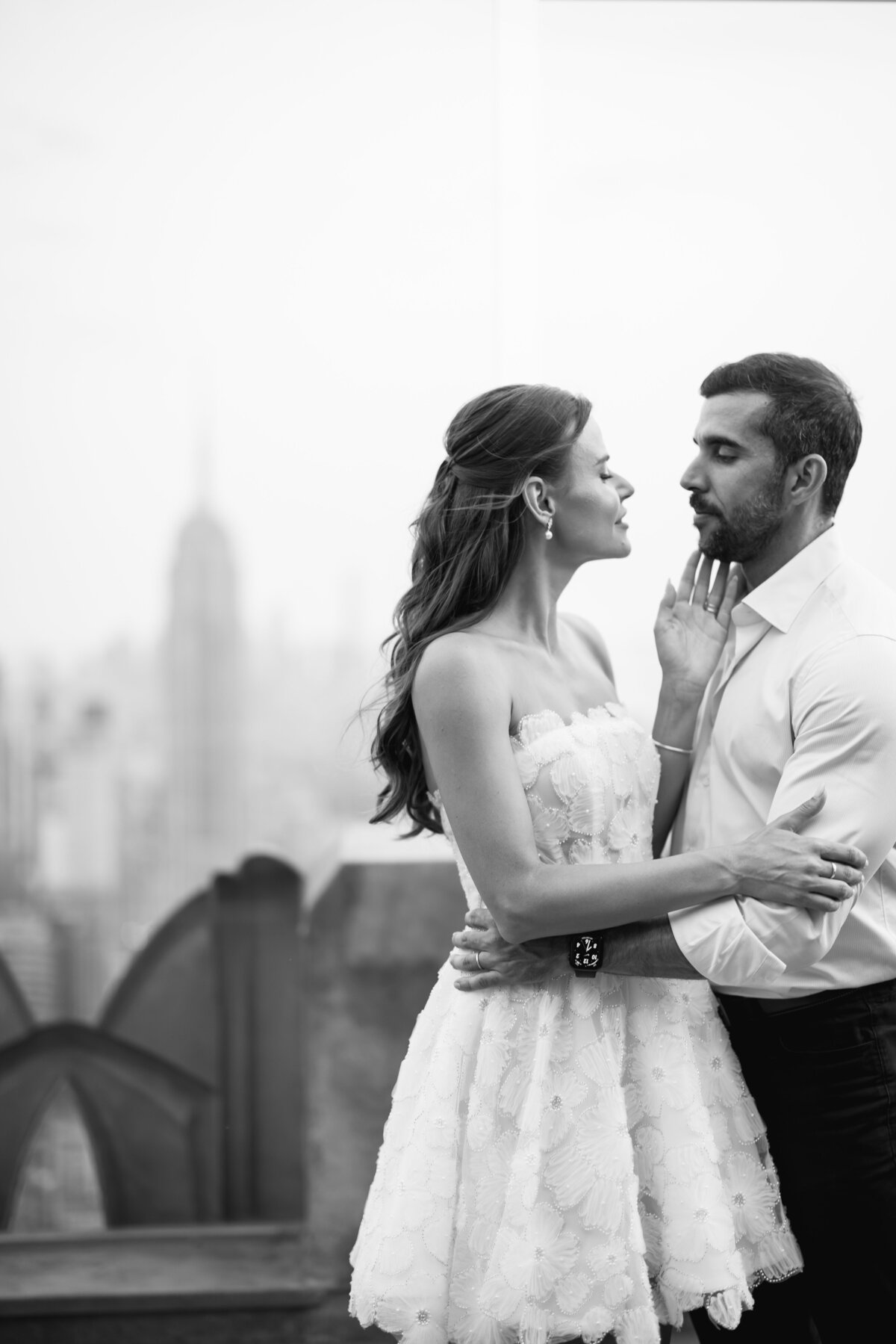 A classic wedding photo of the bride and groom framed against the sunset skyline at Rockefeller Center, showcasing the elegance of the city.