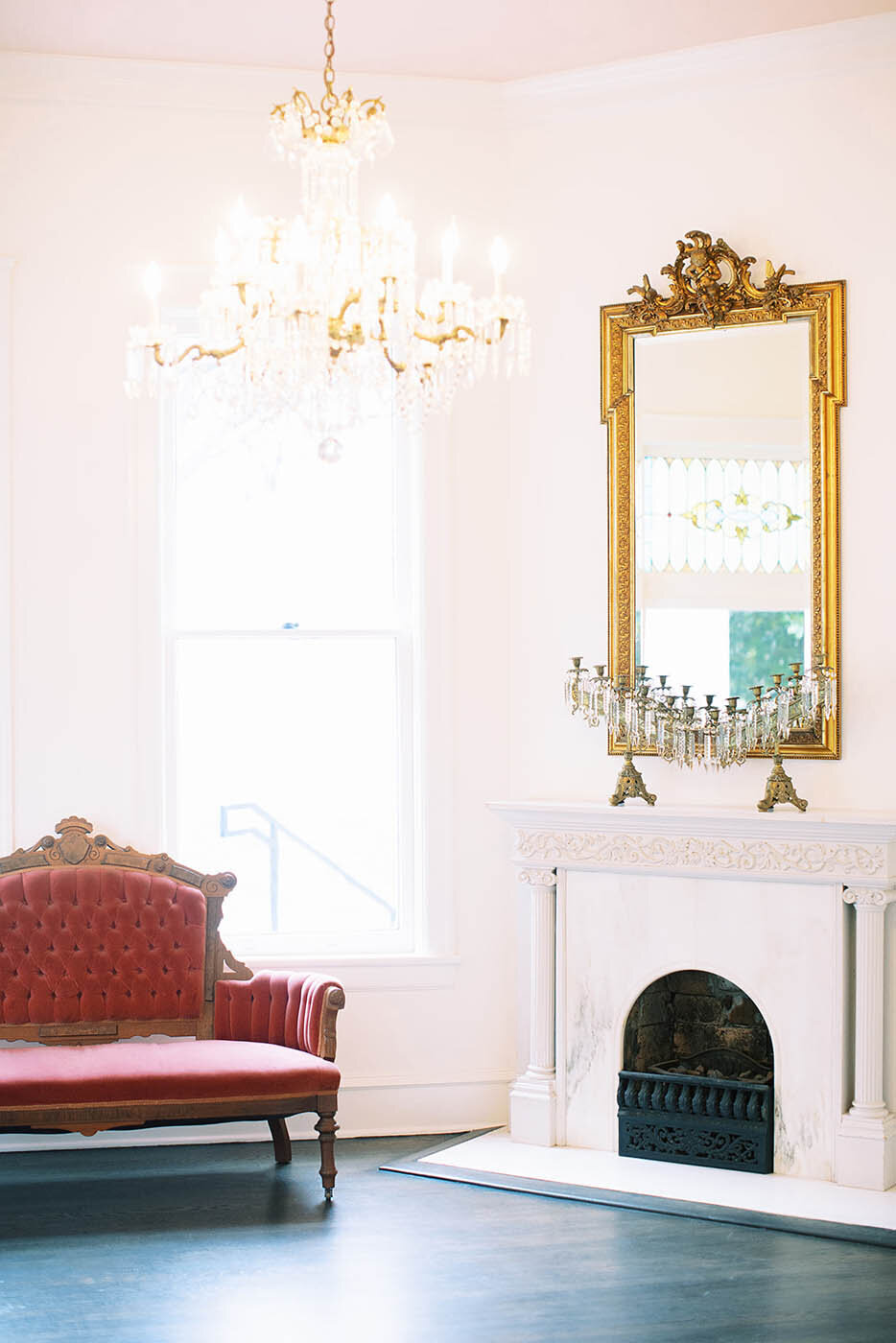 the indoor atrium at woodbine mansion with a fireplace and red couch