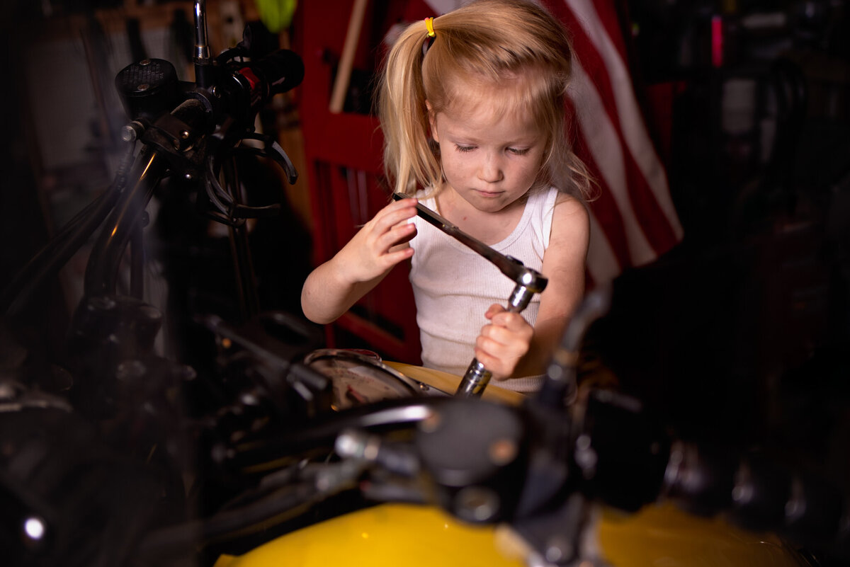 Charming portrait of a young child working on a motorcycle, dressed as a mechanic in a creative setup. Captured in Overland Park, Kansas, this fun and unique setup is ideal for families seeking hands-on and imaginative child photography.