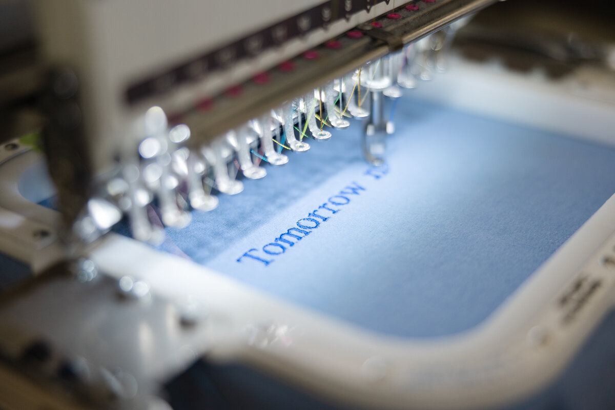 Embroidery machines stitching custom designs onto fabric in studio. Photograph by Yucaipa branding photographer Kaitlyn Dawn Photography.