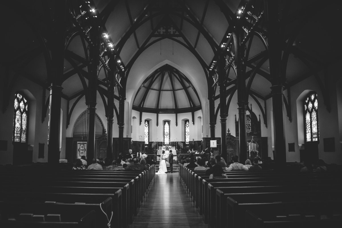bride and groom stand at altar wide black and white portrait of wedding ceremony at St Marks Catholic Church in San Antonio
