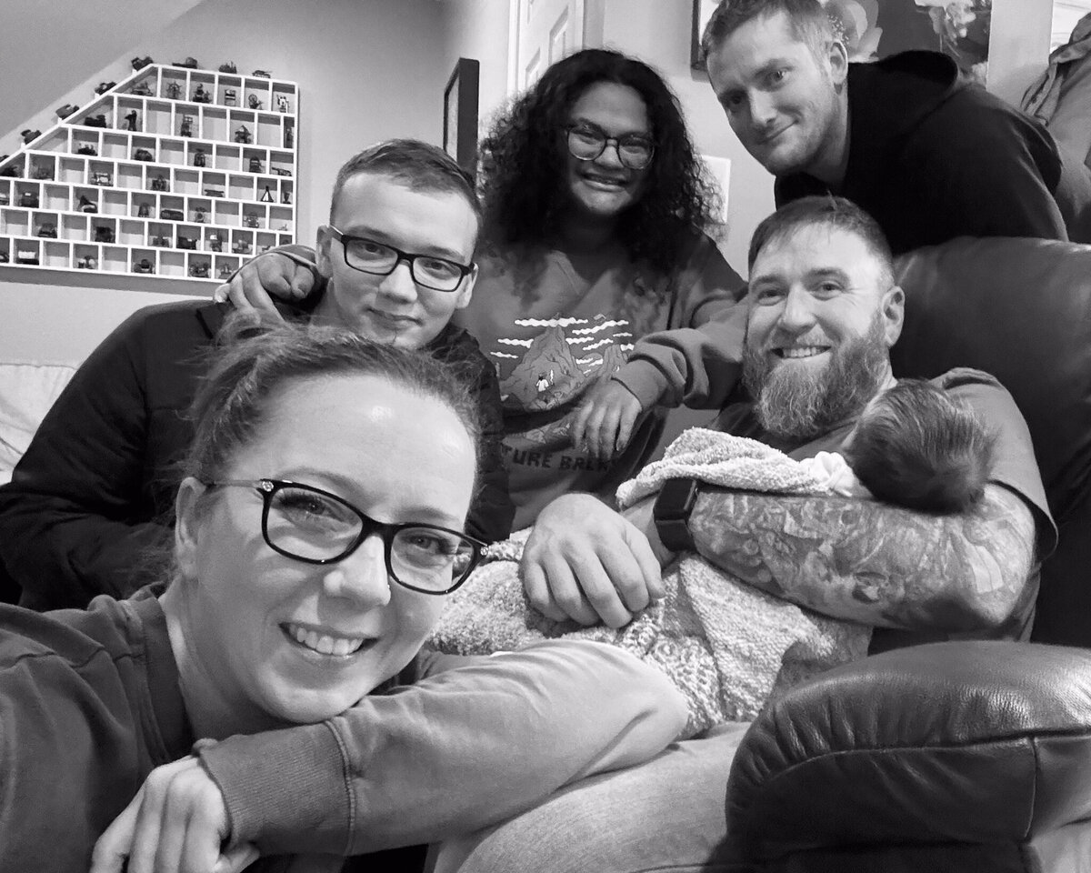 black and white phot of grandparents, son, daughter in law, grandson, and friend looking at the camera smiling