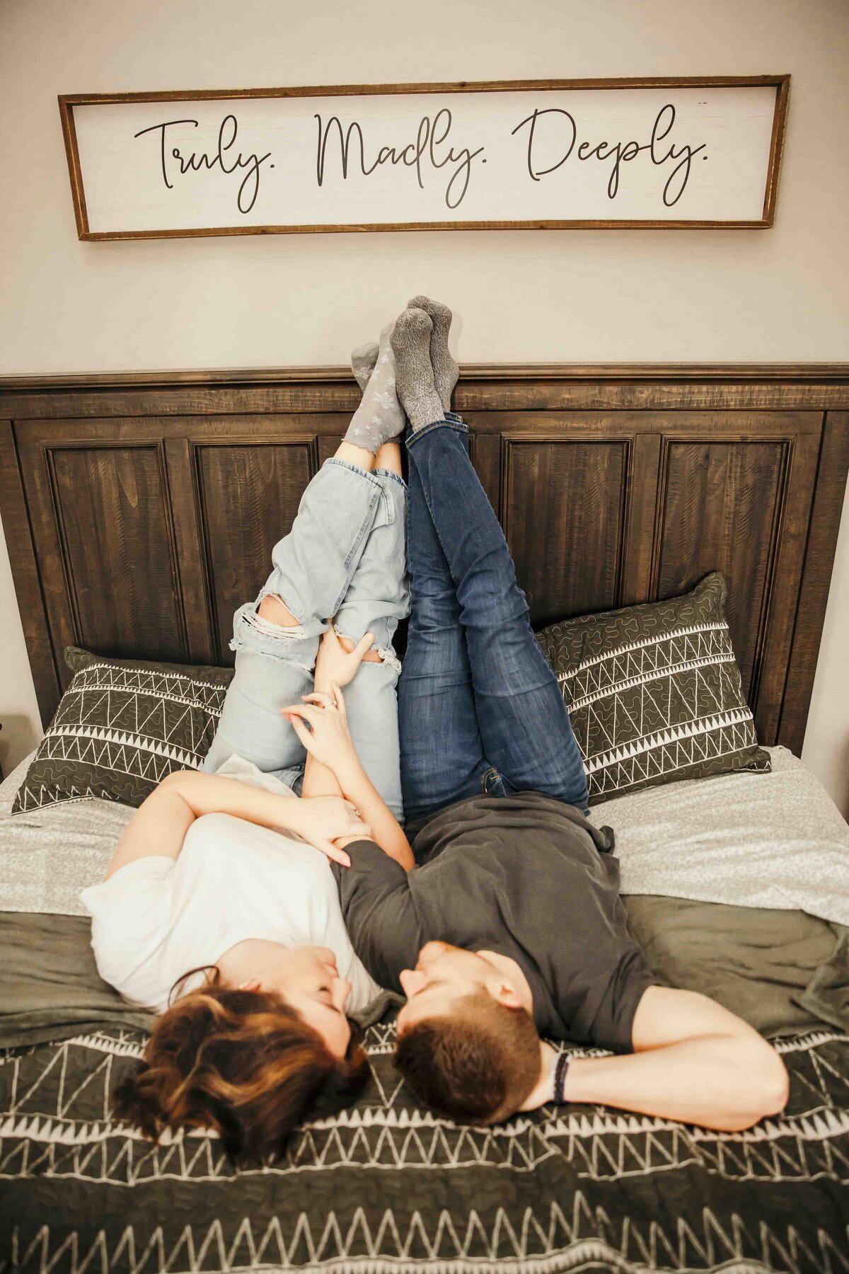 husband and wife laying in bed with their feet up