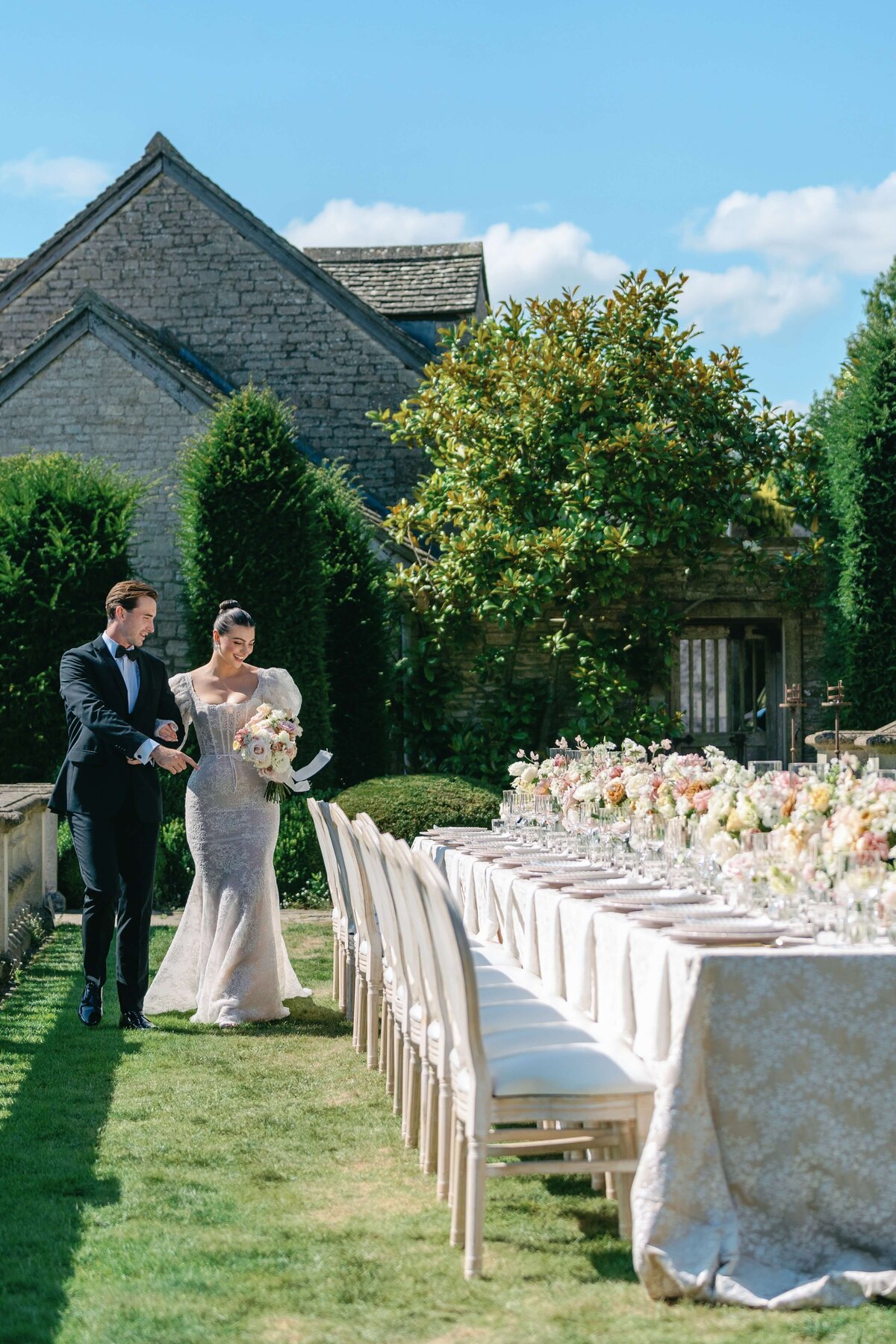 Bride and groom seeing their wedding reception, with long tables covered in floral linens