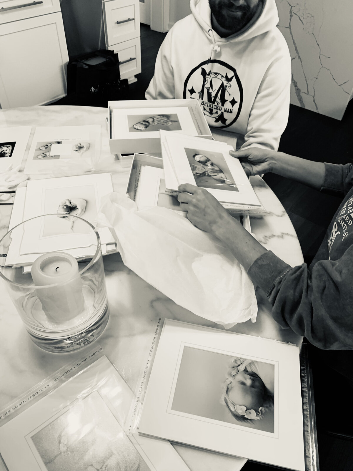 Family holds album of pictures from their newborn session .