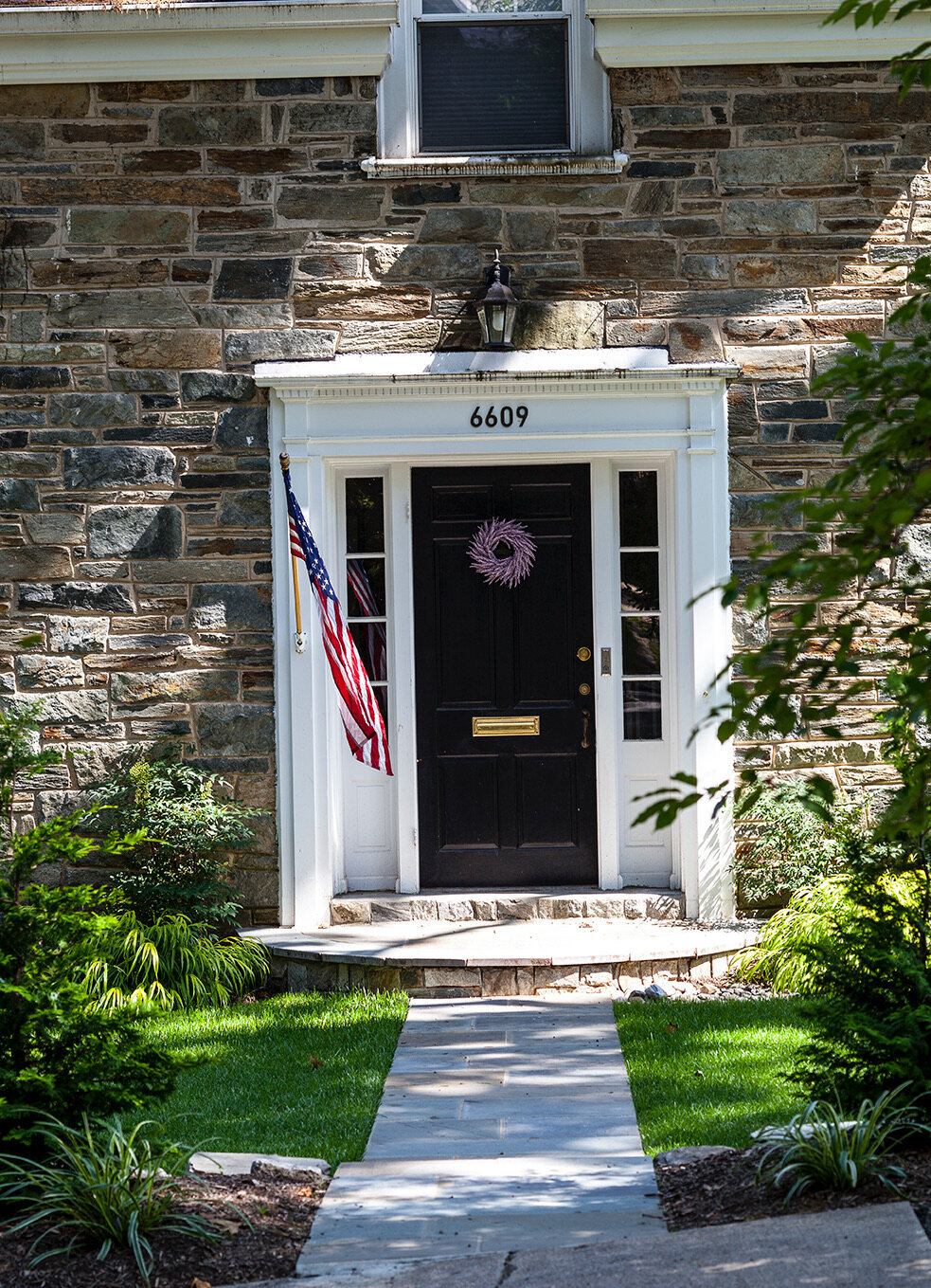 A stately front entrance with an American flag and lush green landscaping.
