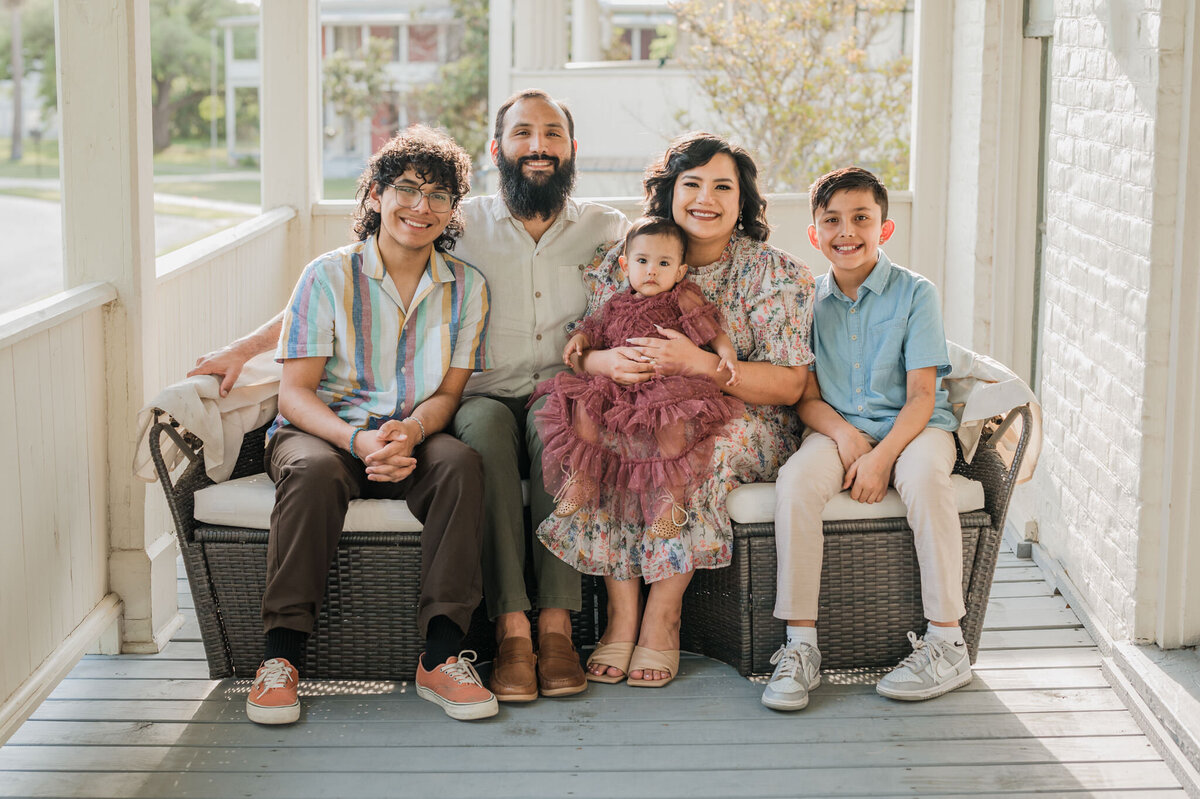 Professional family photography of a family of 5 on a porch couch.