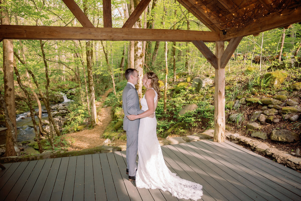 Gatlinburg elopement with bride and groom dancing in a pavilion as the sun sets through the trees casting shadows over the couple