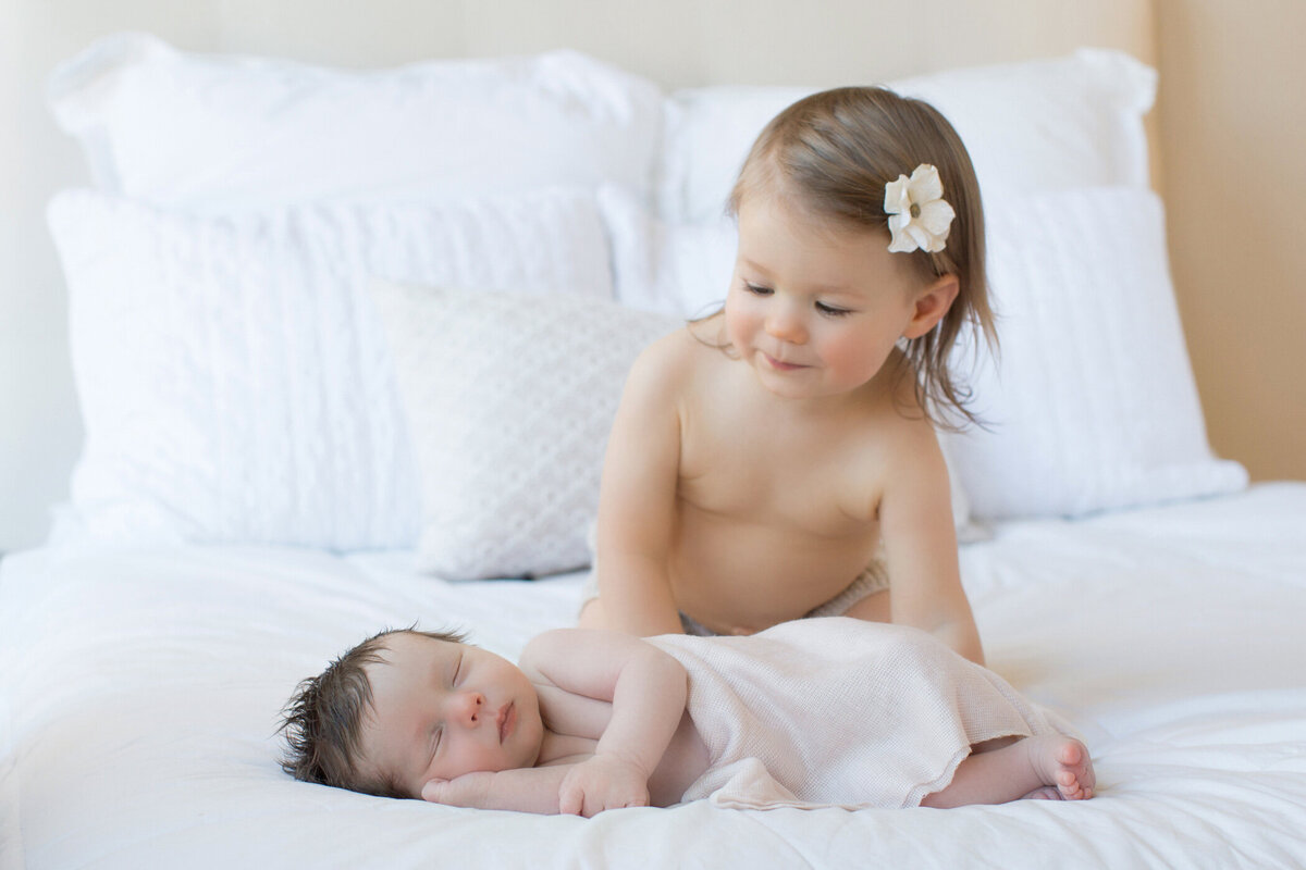 curious_big_sister_looking_at_newborn