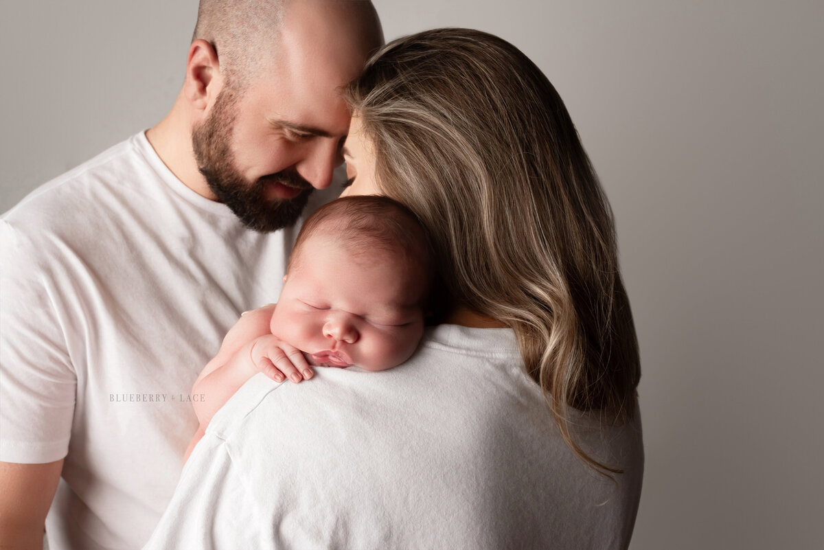 10lb baby boy and hus chunky cheeks pose with mom and dad for newborn photos in Syracuse New york