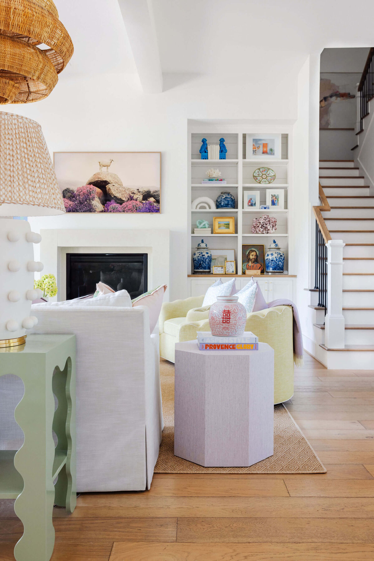 oyster creek studios aryns home pastel purple yellow and green seating and tables in living room with bookshelf