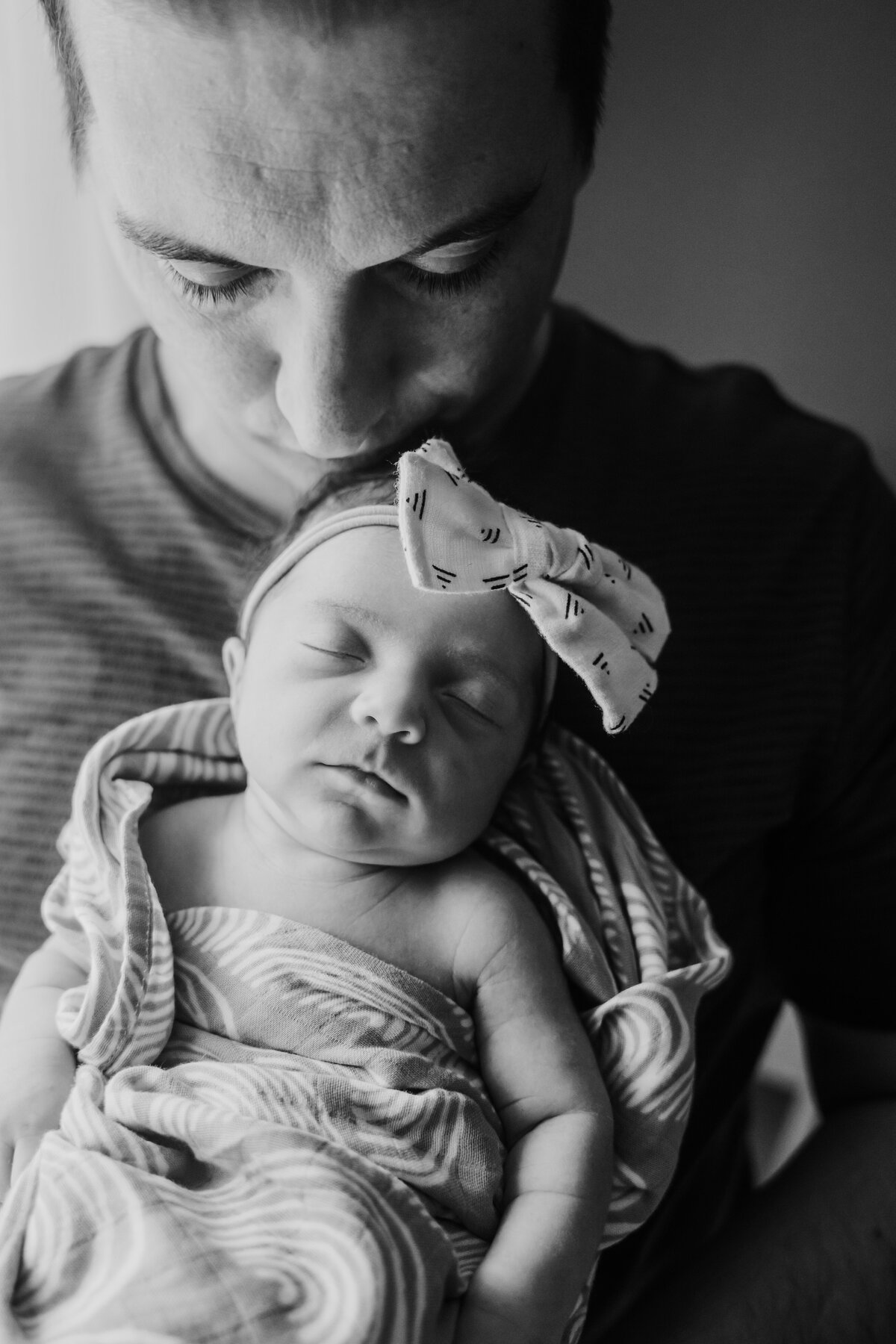 Newborn Photographer, a father holds his baby girl at his chest tenderly