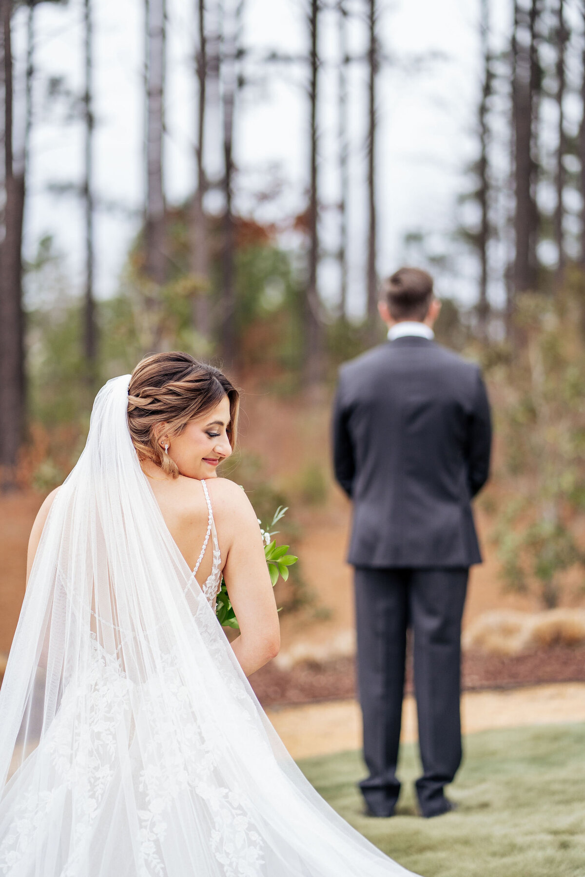 bride looks over her shoulder before first look at the Upchurch in Cary, NC
