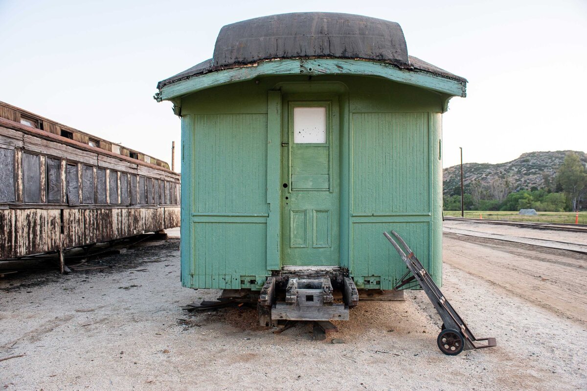 An old wooden green train car in the desert