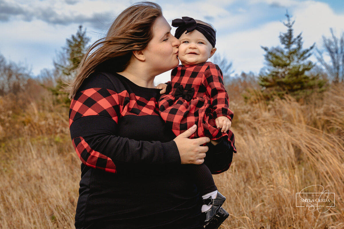 Mom kissing baby daughters cheek while baby laughs
