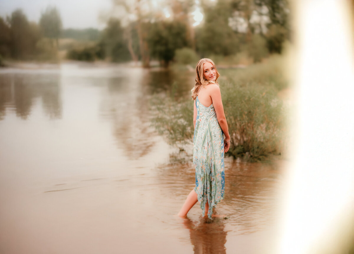 Senior girl in white dress standing in tall grass at Afton State Park near Forest Lake, MN during golden hour.