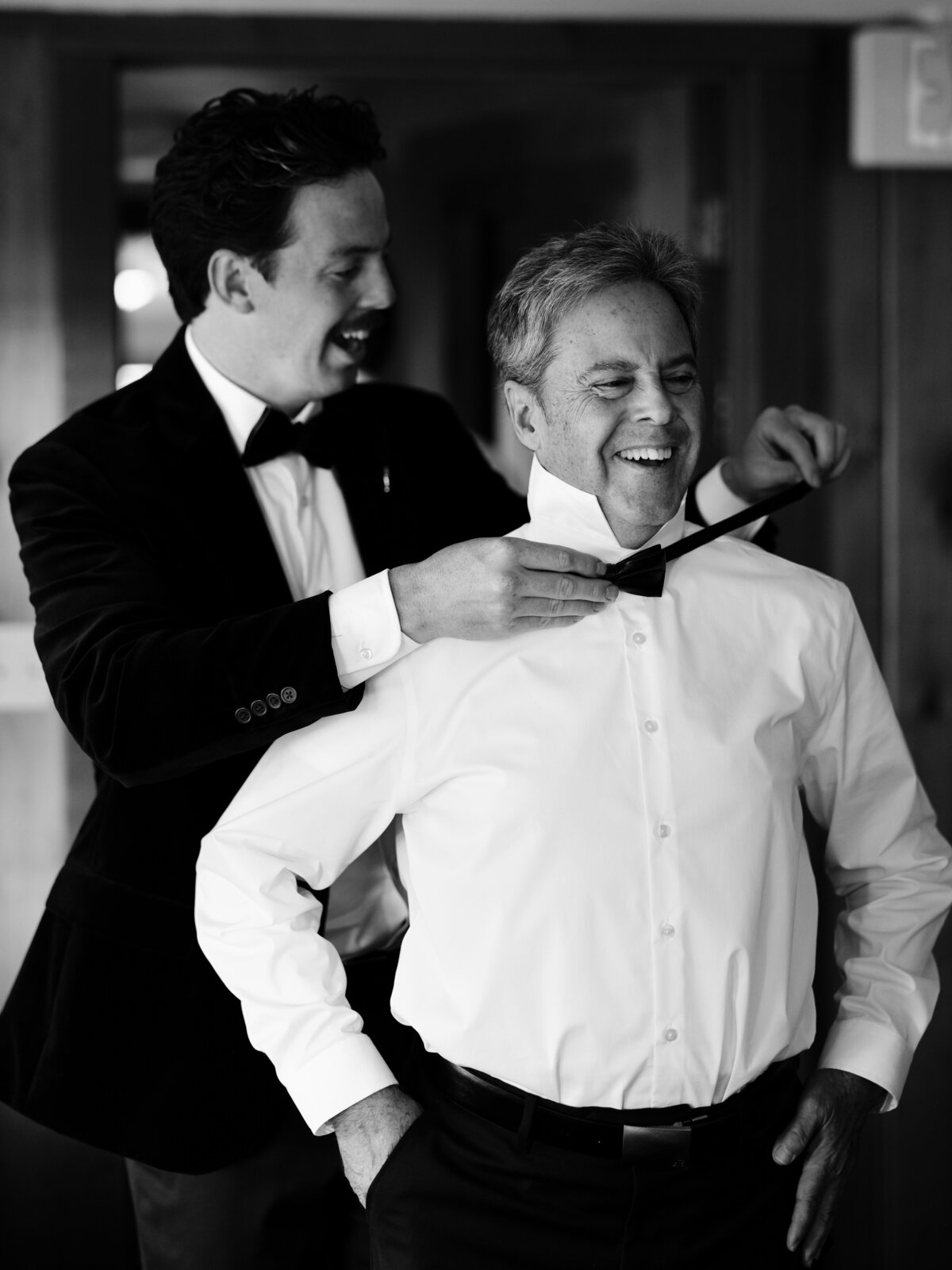 man adjusting bowtie on groomsmen
