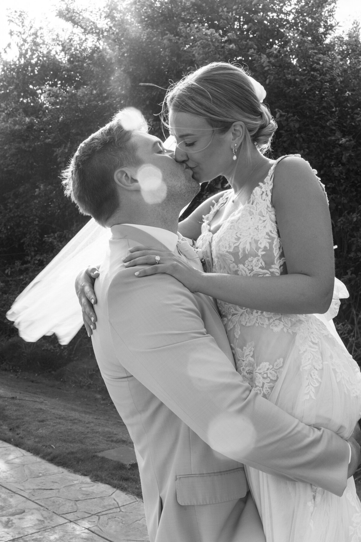 Groom lifts bride for a kiss in backlit black-and-white photo at Cancun destination wedding.