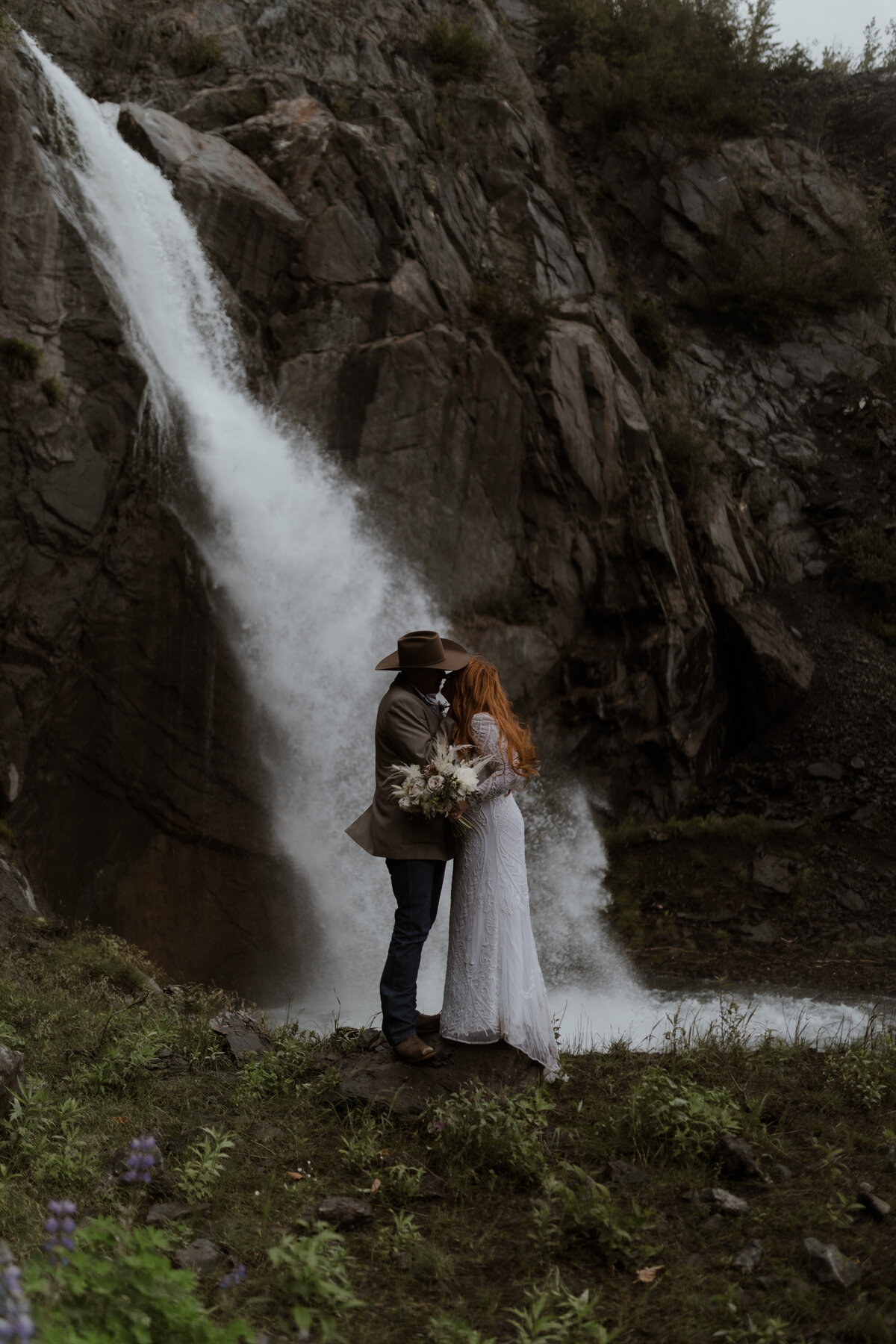 Wedding couple kissing under waterfall