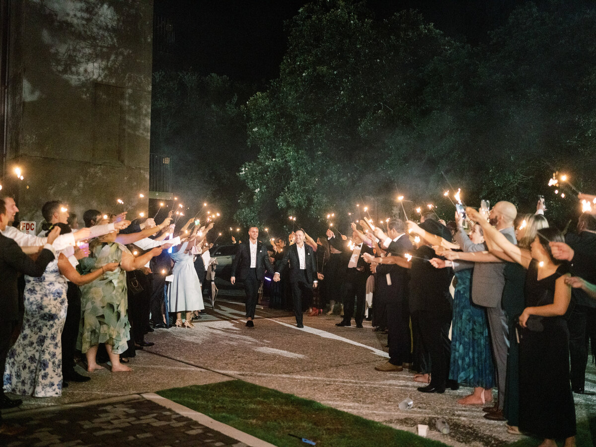 A vibrant crowd cheers with sparklers at night, creating a magical atmosphere for a couple celebrating their special moment surrounded by friends and family.