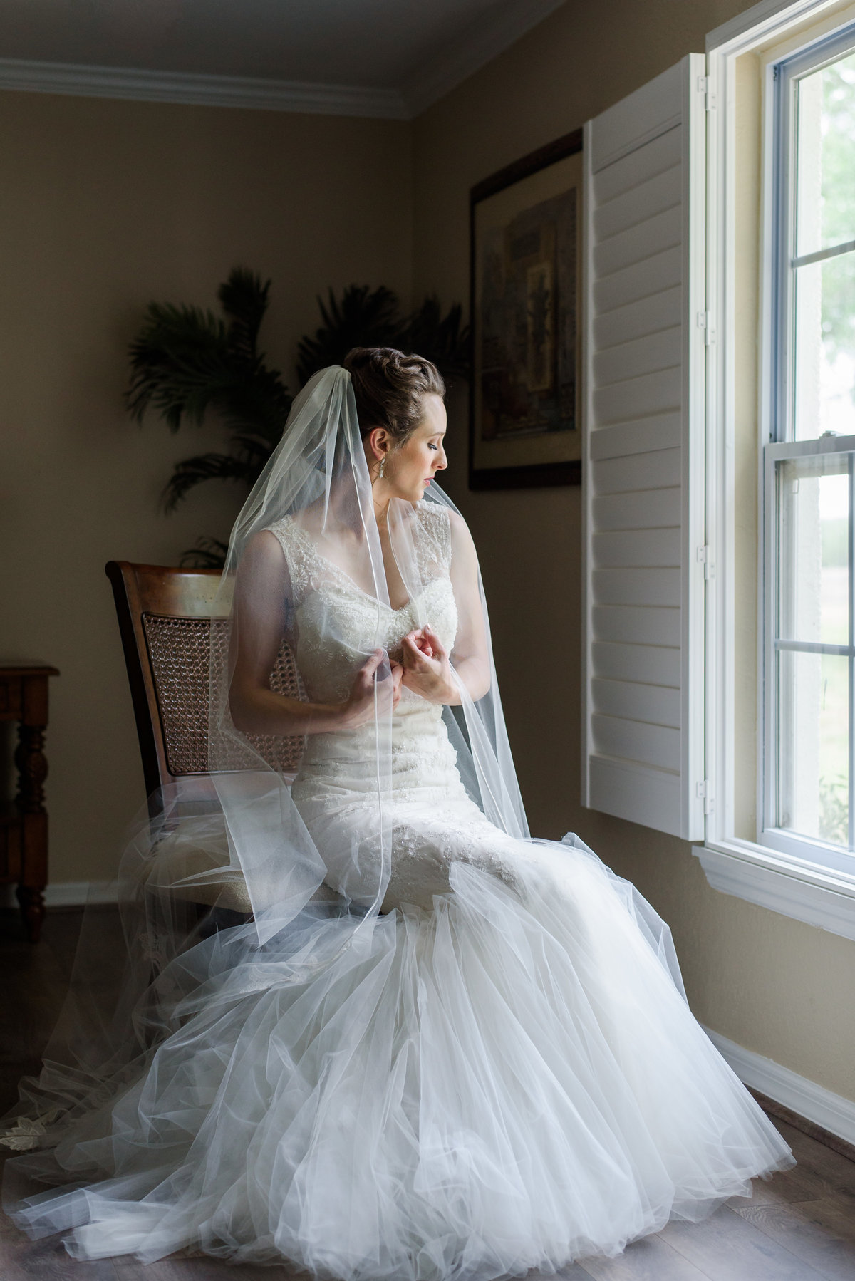 Bride sitting in window light as she looks out the window