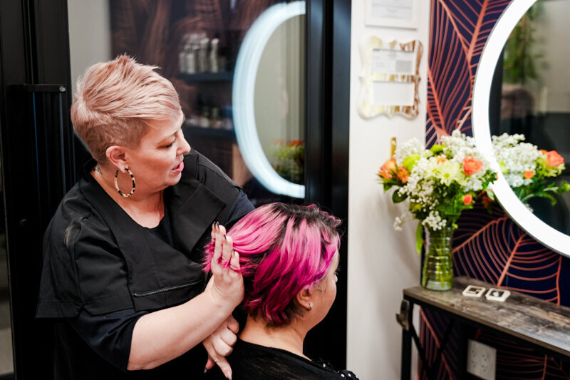 Hairstylist in salon consulting with a client with bright pink hair